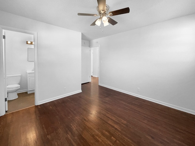 unfurnished bedroom featuring ensuite bath, ceiling fan, and dark hardwood / wood-style floors