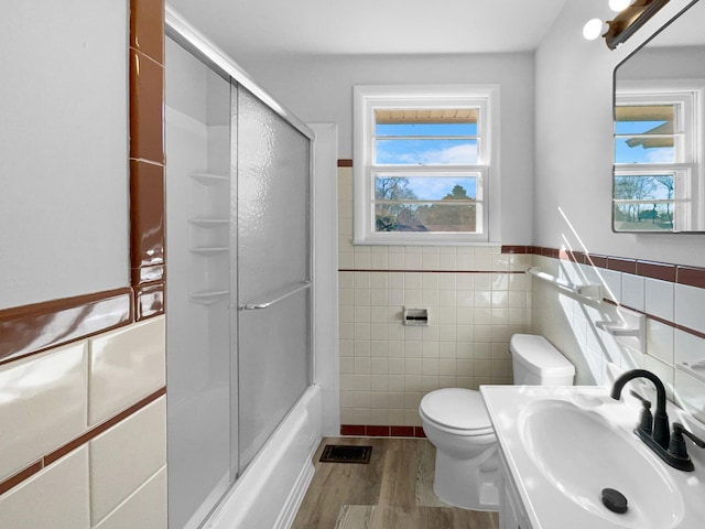 full bathroom featuring tile walls, hardwood / wood-style floors, plenty of natural light, and sink