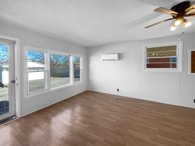 spare room with a textured ceiling, ceiling fan, a wall mounted air conditioner, and dark hardwood / wood-style flooring