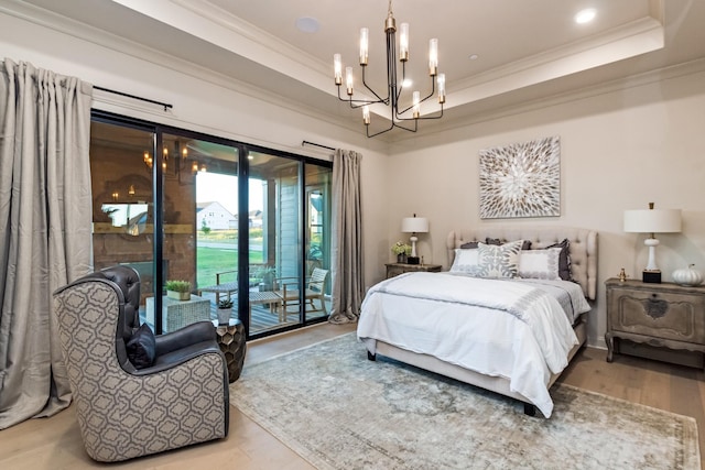 bedroom with crown molding, a chandelier, light wood-type flooring, a tray ceiling, and access to exterior