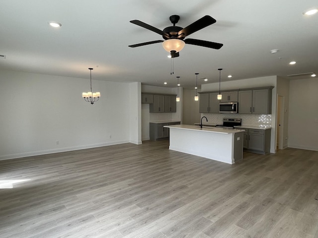 kitchen with stainless steel appliances, sink, tasteful backsplash, a center island with sink, and gray cabinetry