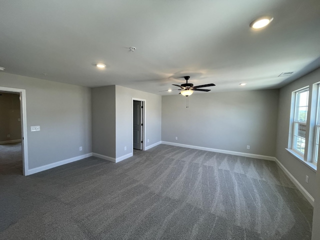 spare room featuring ceiling fan and dark carpet