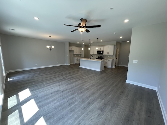 unfurnished living room with sink, dark hardwood / wood-style flooring, and ceiling fan with notable chandelier