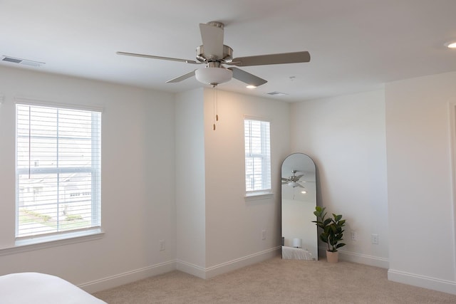 unfurnished bedroom featuring ceiling fan, light carpet, and multiple windows