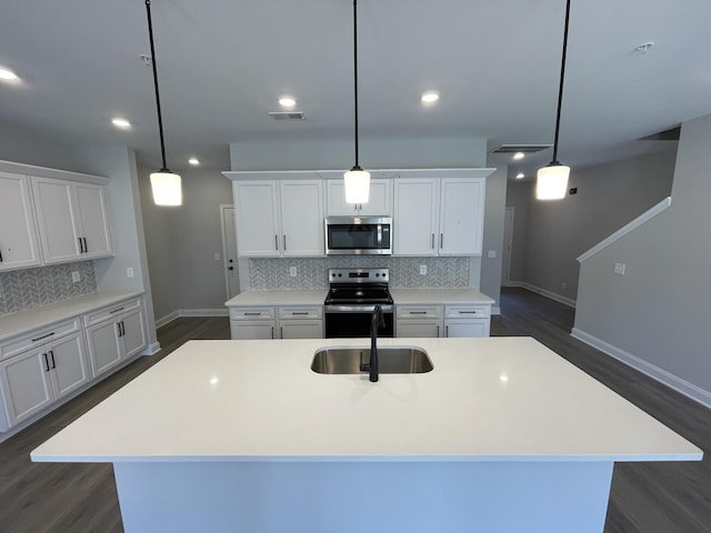 kitchen featuring hanging light fixtures, an island with sink, white cabinetry, appliances with stainless steel finishes, and sink