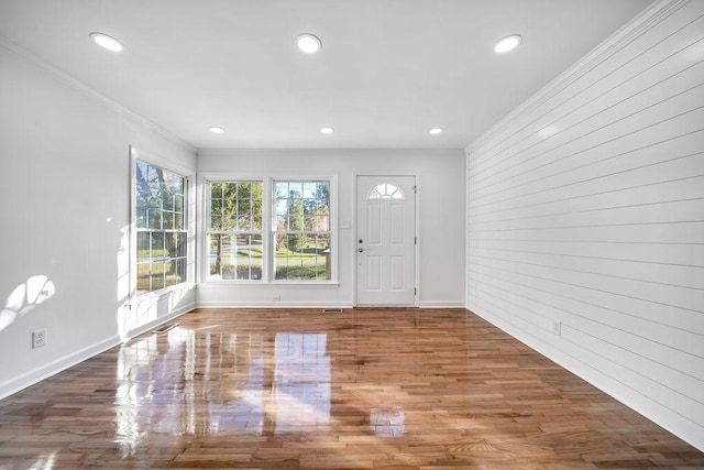 entrance foyer featuring brick wall, ornamental molding, and hardwood / wood-style floors