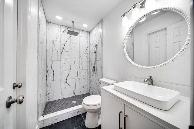 bathroom with tiled shower, vanity, tile patterned floors, and toilet