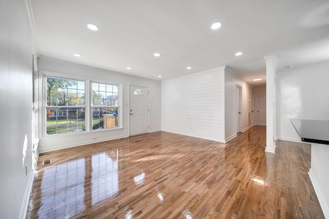 unfurnished living room with hardwood / wood-style floors and crown molding