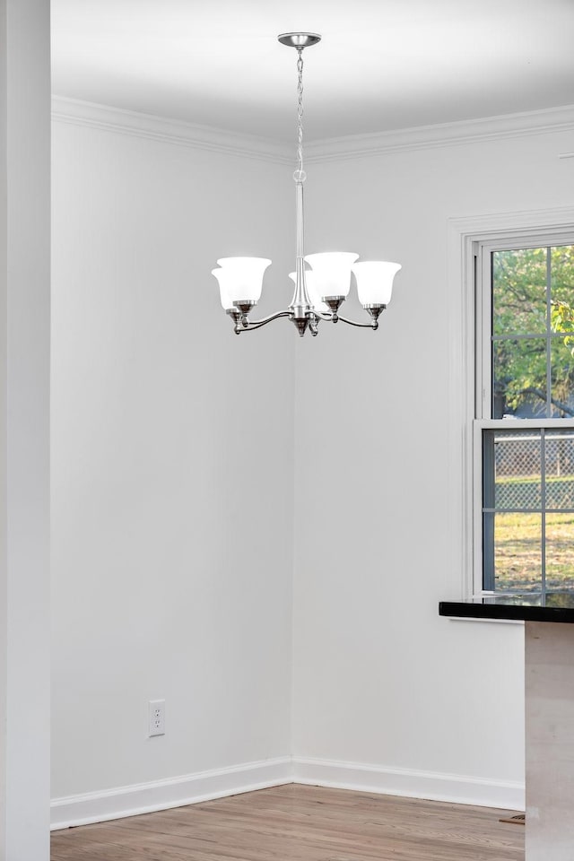 unfurnished dining area featuring ornamental molding, a chandelier, and hardwood / wood-style flooring