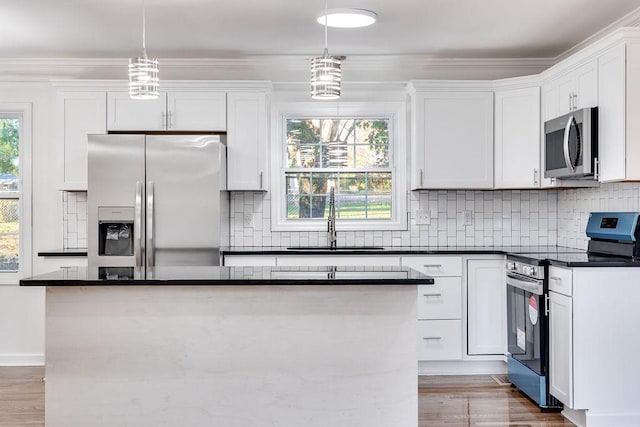 kitchen featuring decorative light fixtures, a center island, appliances with stainless steel finishes, and white cabinetry