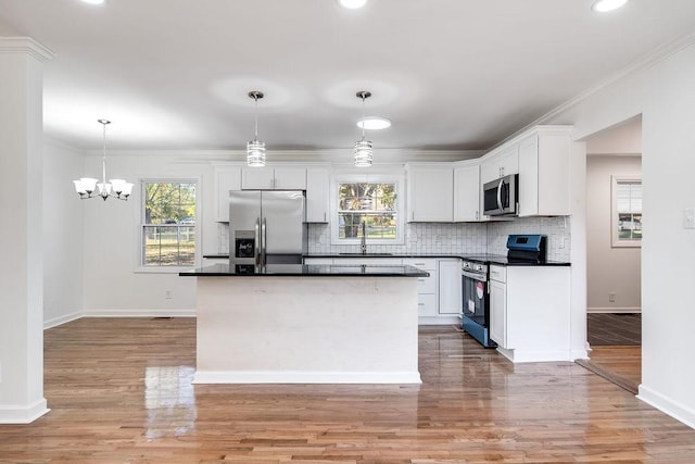 kitchen with decorative light fixtures, a center island, appliances with stainless steel finishes, and white cabinetry