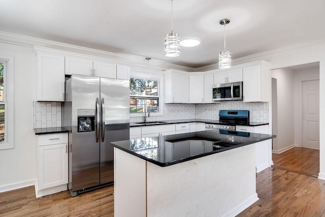 kitchen with decorative light fixtures, a kitchen island, white cabinetry, appliances with stainless steel finishes, and sink