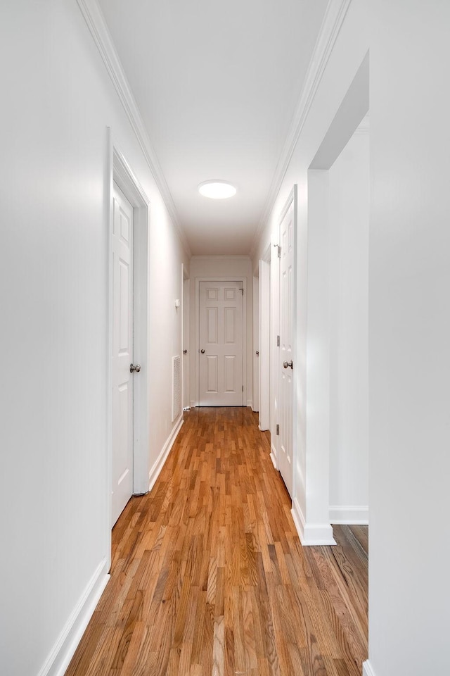 corridor featuring light wood-type flooring and ornamental molding