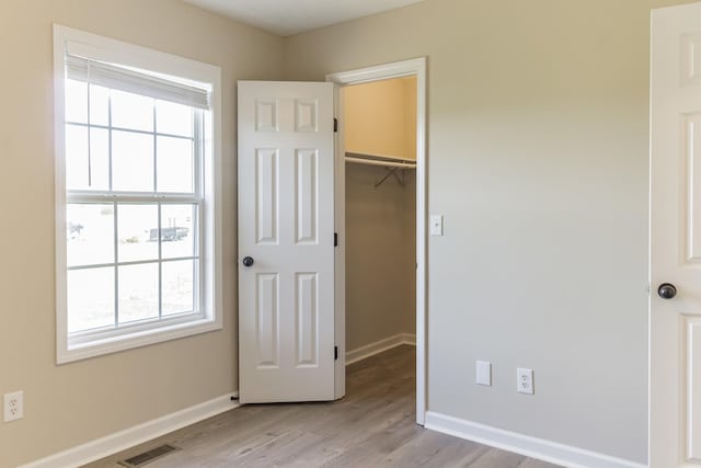 unfurnished bedroom featuring a closet, light hardwood / wood-style floors, and a spacious closet