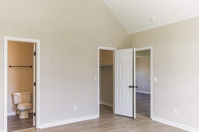 unfurnished bedroom with ensuite bathroom, a walk in closet, a closet, and light hardwood / wood-style floors