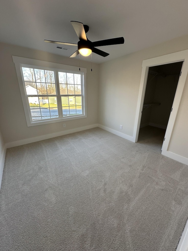 unfurnished bedroom featuring ceiling fan, light colored carpet, a spacious closet, and a closet