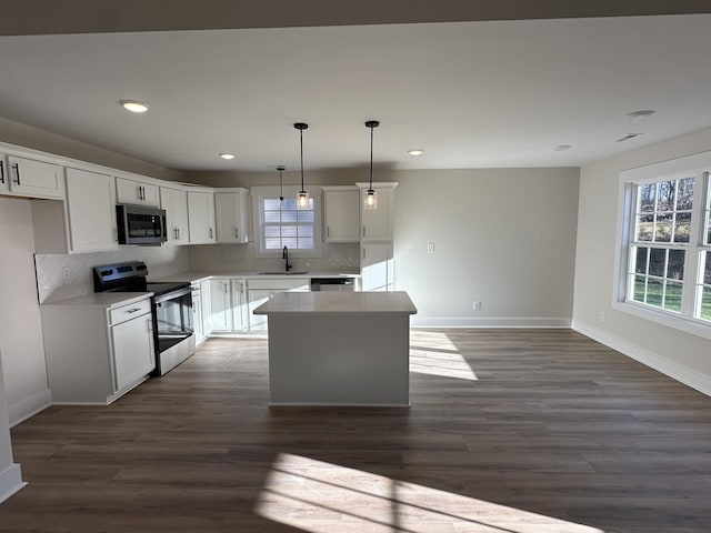 kitchen featuring stainless steel appliances, sink, white cabinets, a kitchen island, and pendant lighting