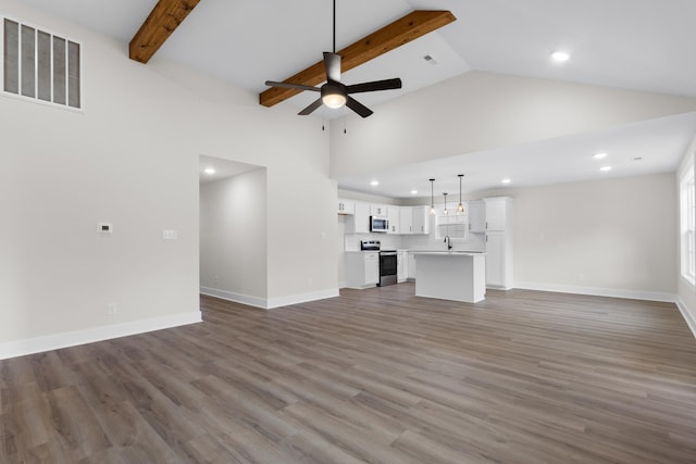 unfurnished living room featuring ceiling fan, a towering ceiling, sink, beamed ceiling, and hardwood / wood-style flooring