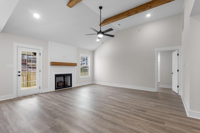 unfurnished living room with a healthy amount of sunlight, a fireplace, beamed ceiling, and hardwood / wood-style flooring