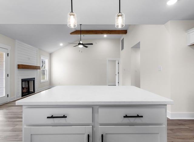 kitchen with ceiling fan, white cabinetry, a fireplace, and hanging light fixtures