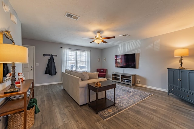 living room featuring ceiling fan, a textured ceiling, and dark hardwood / wood-style floors