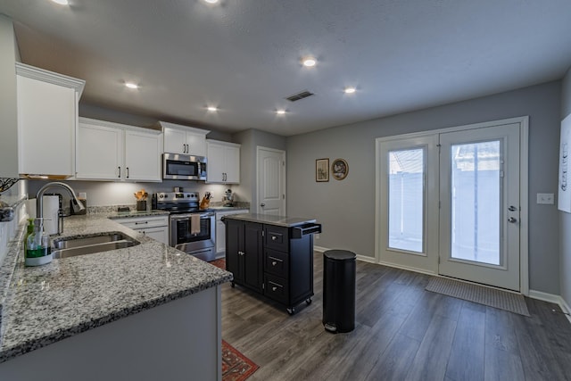 kitchen featuring appliances with stainless steel finishes, a center island, dark wood-type flooring, white cabinets, and sink