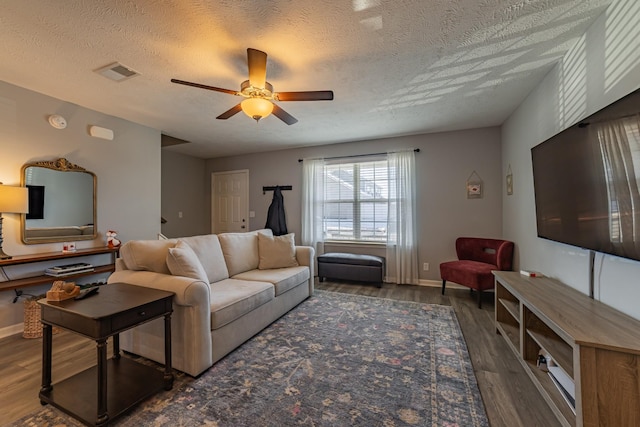 living room with ceiling fan, dark hardwood / wood-style flooring, and a textured ceiling