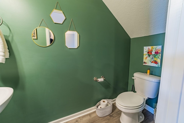 bathroom featuring a textured ceiling, toilet, lofted ceiling, and wood-type flooring