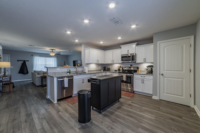 kitchen featuring white cabinets, kitchen peninsula, stainless steel appliances, and a center island