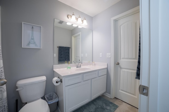 bathroom with toilet, vanity, and tile patterned floors