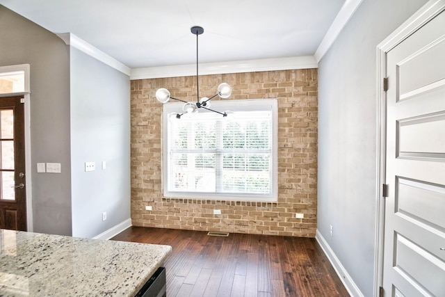 unfurnished dining area featuring brick wall, a notable chandelier, crown molding, and dark wood-type flooring