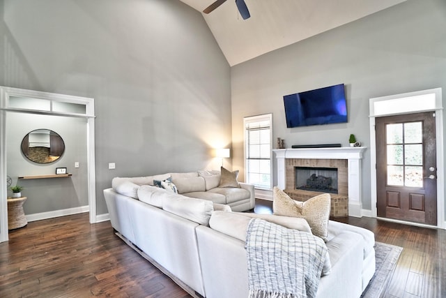 living room featuring a fireplace, ceiling fan, a wealth of natural light, and dark wood-type flooring