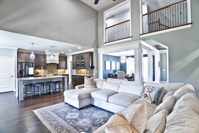 living room featuring a high ceiling, ceiling fan, and dark hardwood / wood-style floors