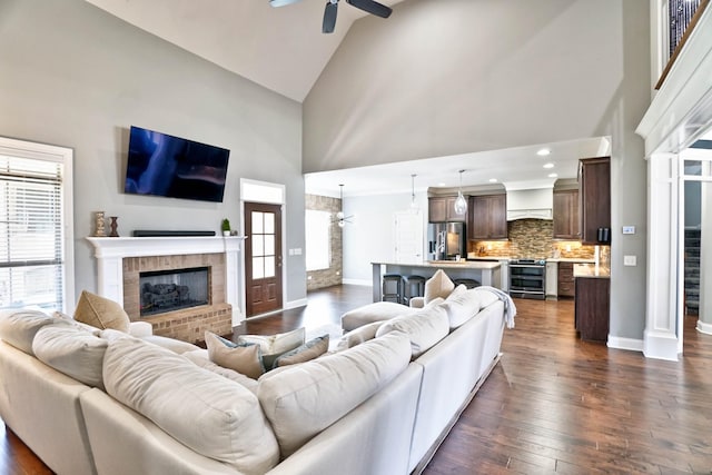 living room featuring ceiling fan, dark wood-type flooring, high vaulted ceiling, and a fireplace