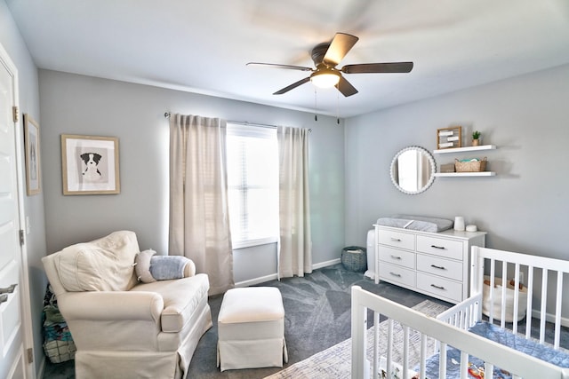 bedroom featuring ceiling fan, a crib, and dark carpet