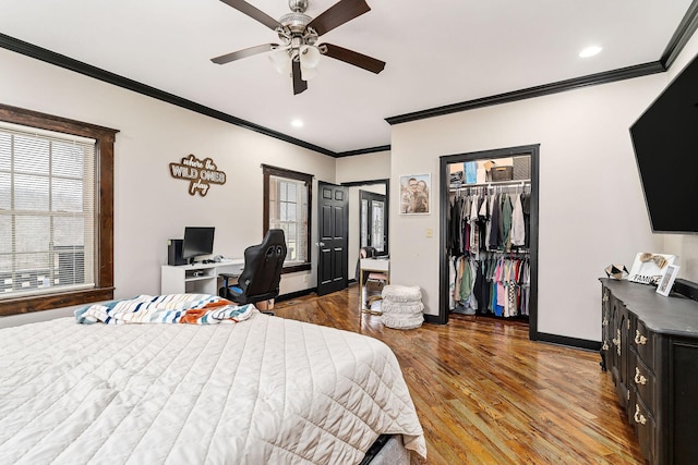 bedroom with a spacious closet, ceiling fan, hardwood / wood-style flooring, ornamental molding, and a closet