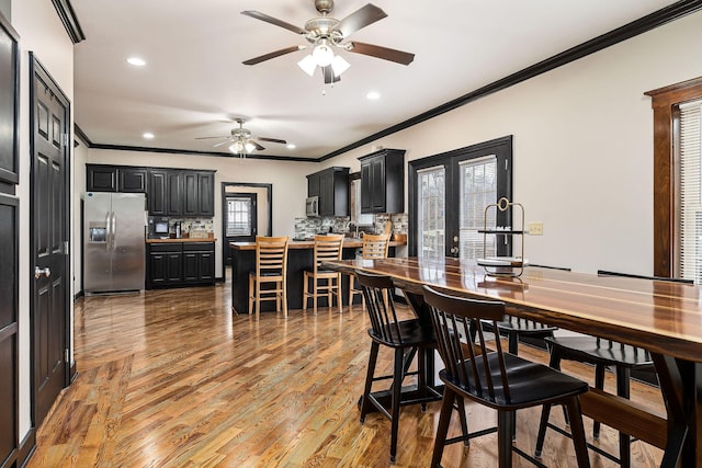 dining room with wood-type flooring, french doors, ornamental molding, and ceiling fan