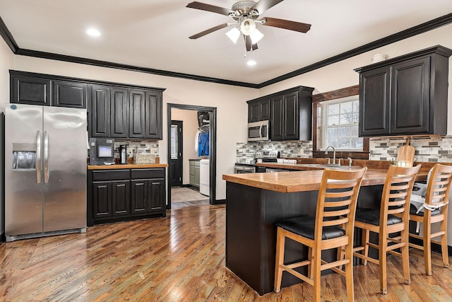 kitchen featuring stainless steel appliances, wood counters, hardwood / wood-style flooring, sink, and tasteful backsplash