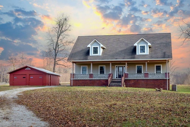 cape cod house featuring a porch, an outbuilding, a garage, central AC unit, and a yard