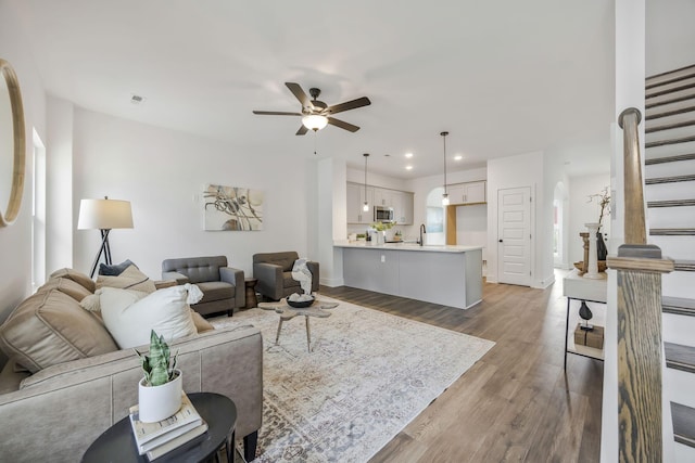 living room with ceiling fan, a wealth of natural light, wood-type flooring, and sink