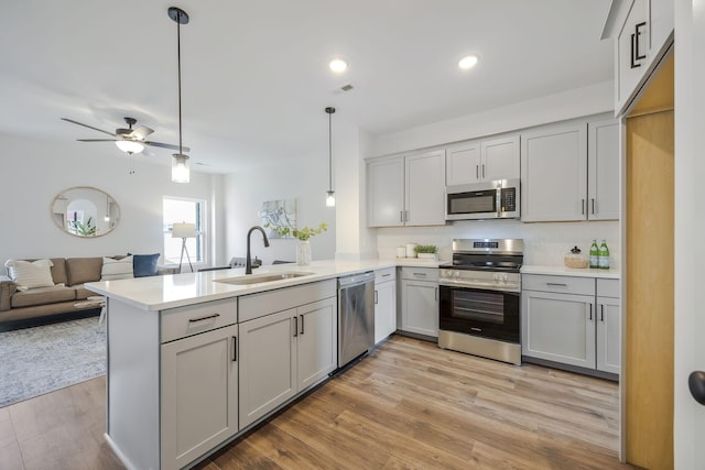 kitchen with decorative light fixtures, sink, kitchen peninsula, and stainless steel appliances