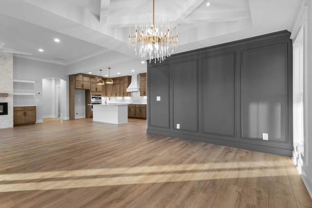 unfurnished living room featuring light hardwood / wood-style floors, an inviting chandelier, crown molding, a fireplace, and built in features