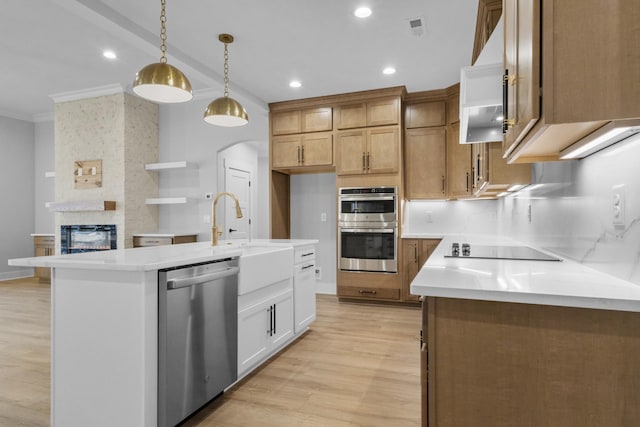 kitchen with stainless steel appliances, decorative light fixtures, white cabinetry, tasteful backsplash, and a kitchen island with sink