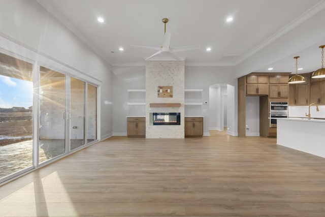 unfurnished living room with sink, a wealth of natural light, crown molding, and built in features