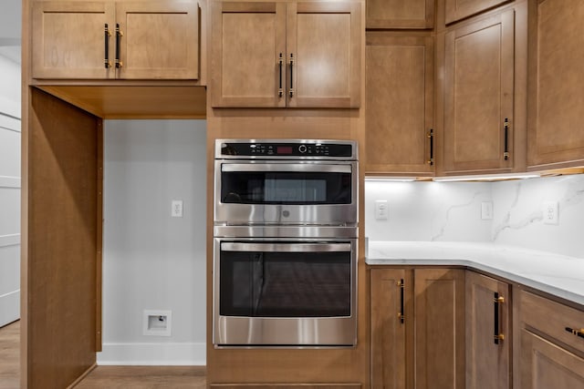 kitchen featuring double oven, light hardwood / wood-style flooring, and backsplash