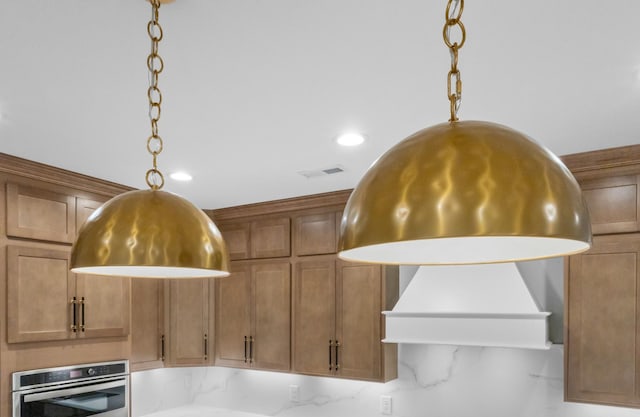 room details featuring light stone countertops, oven, tasteful backsplash, and hanging light fixtures