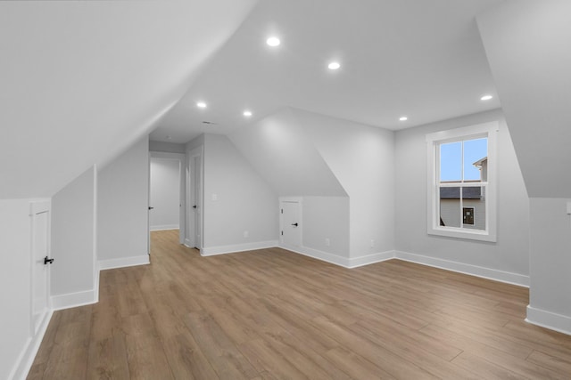 additional living space featuring lofted ceiling and light hardwood / wood-style floors