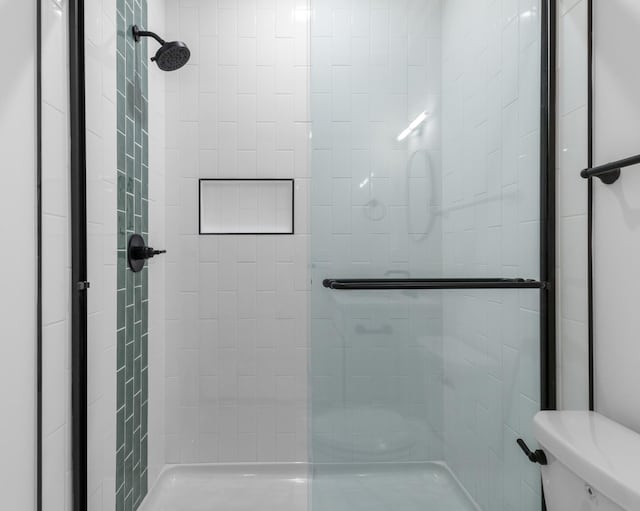 bathroom with a tile shower and toilet