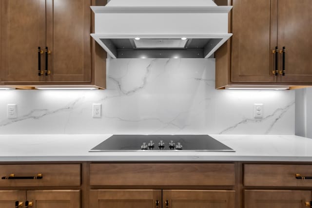 kitchen featuring backsplash, black electric stovetop, and custom exhaust hood