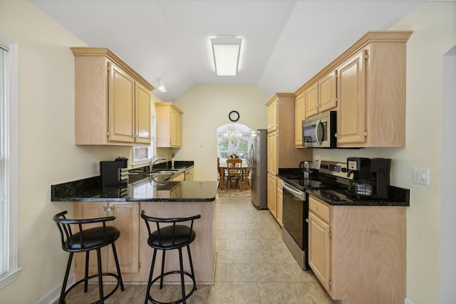 kitchen with stainless steel appliances, sink, lofted ceiling, and light brown cabinetry